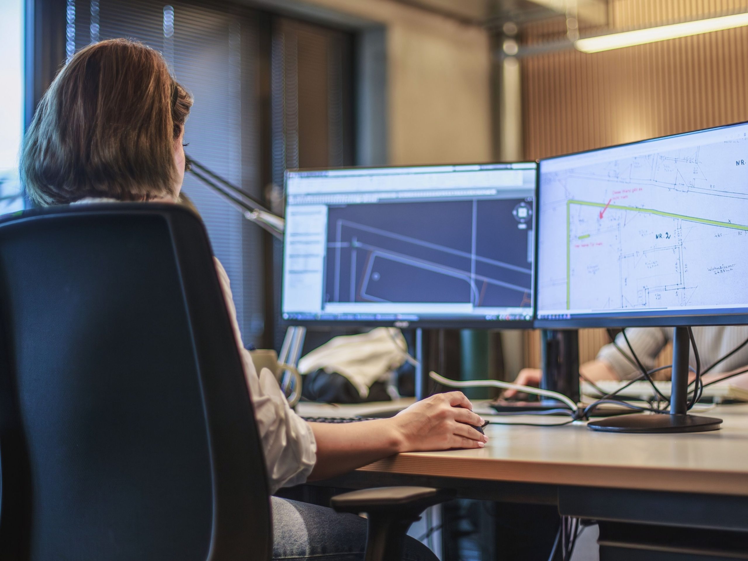 Architektin der 1000hands AG zeichnet am Schreibtisch einen detaillierten 2D-Grundriss auf Basis eines Bestandsplanes.