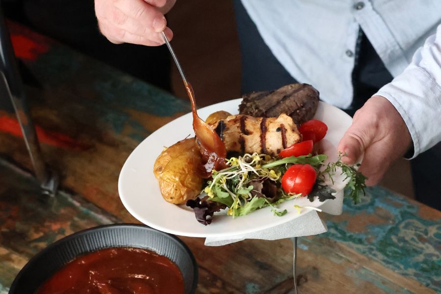 Mitarbeiter füllt seinen Teller mit leckeren Speisen am festlich angerichteten Buffet.