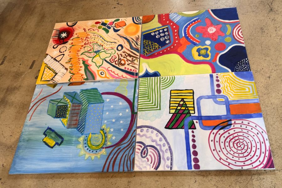 Vier Leinwände bilden ein farbenfrohes Gemeinschaftsgemälde, Symbol für Vielfalt und Teamgeist bei der 1000hands AG.