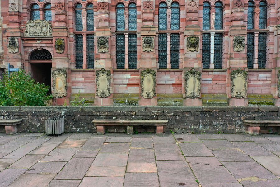 Fassadenausschnitt von Schloss Heidelberg mit reich verzierten Gebäudedetails und Sitzbänken im Vordergrund.