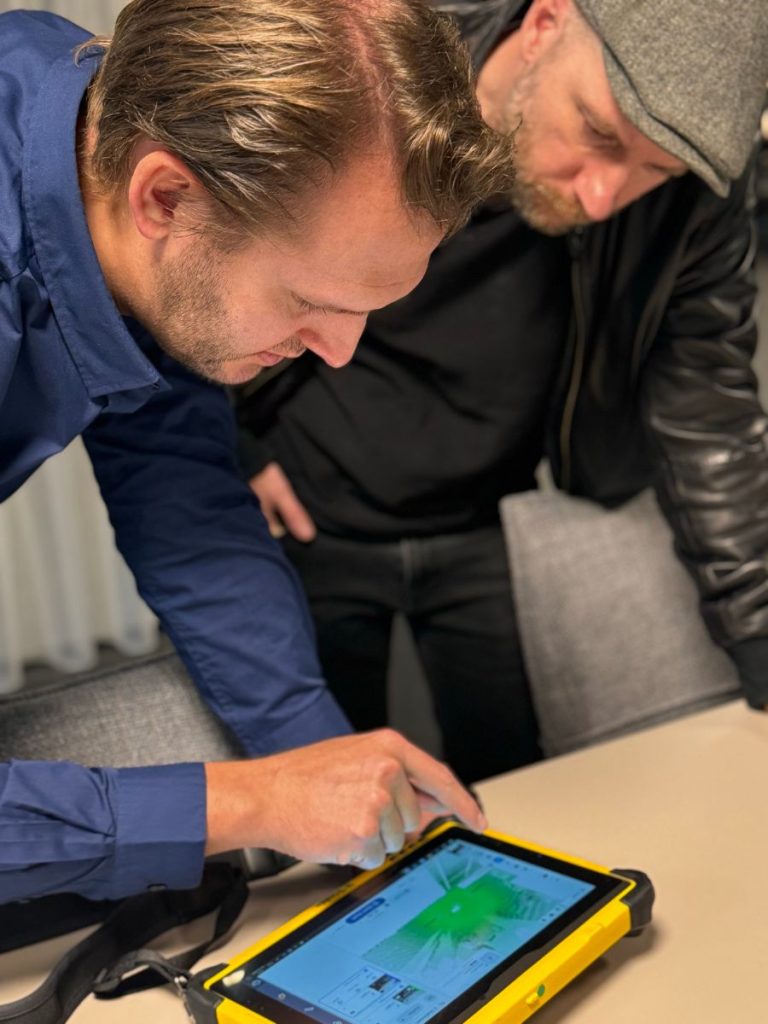 Ein 1000hands Mitarbeiter aus dem 3D und BIM Team weist René Rissland in den Trimble X7 ein und zeigt auf die Punktwolke.